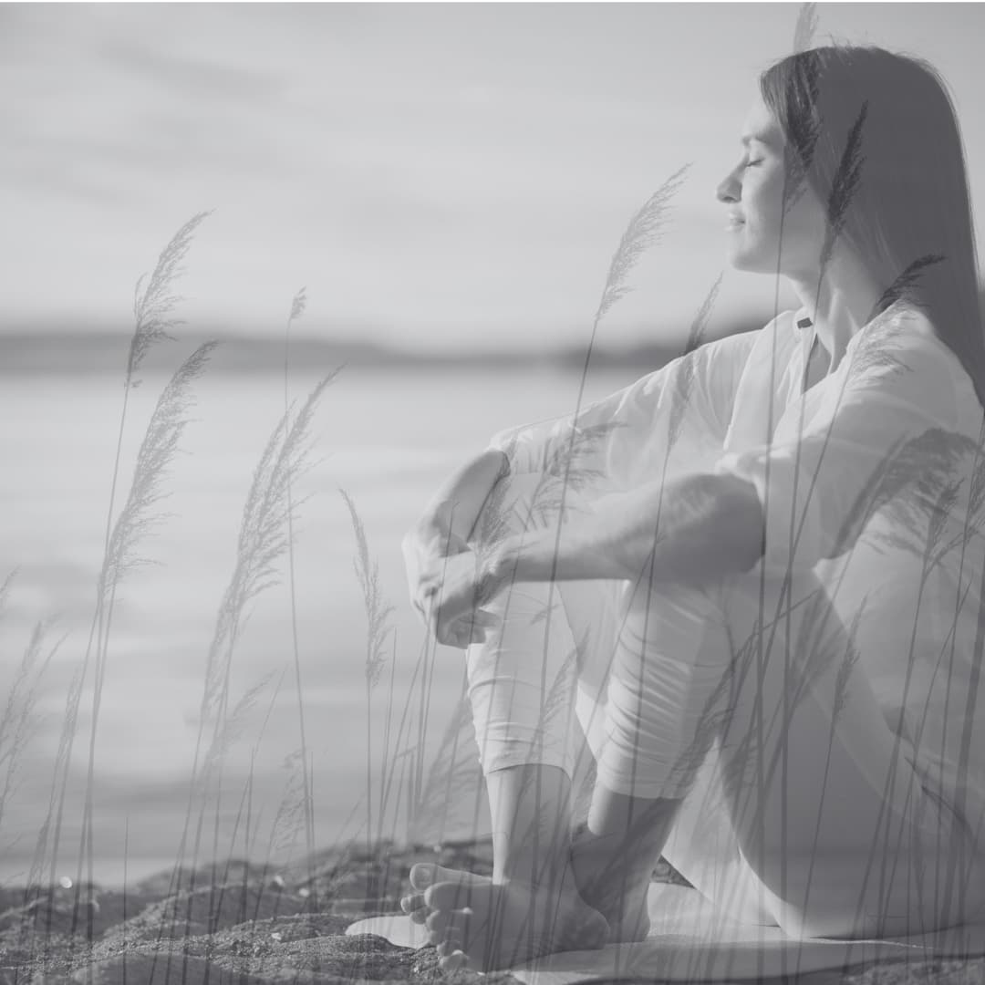 A woman sitting by the sea, looking out, calm and reflective